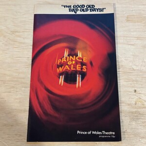 Pode incluir: Uma capa de programa de teatro vintage com o texto "THE GOOD OLD BAD OLD DAYS!". A capa apresenta um design abstrato vermelho e preto com as palavras "PRINCE OF WALES" em dourado. A parte inferior da capa diz "Prince of Wales Theatre programme 10p".
