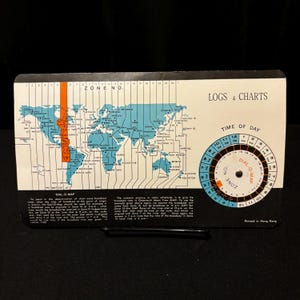 May include: A vintage "Dial-O-Map" time zone chart with a world map in blue and white. The chart includes a rotating dial for time conversion and the text "Logs & Charts". Printed in Hong Kong.