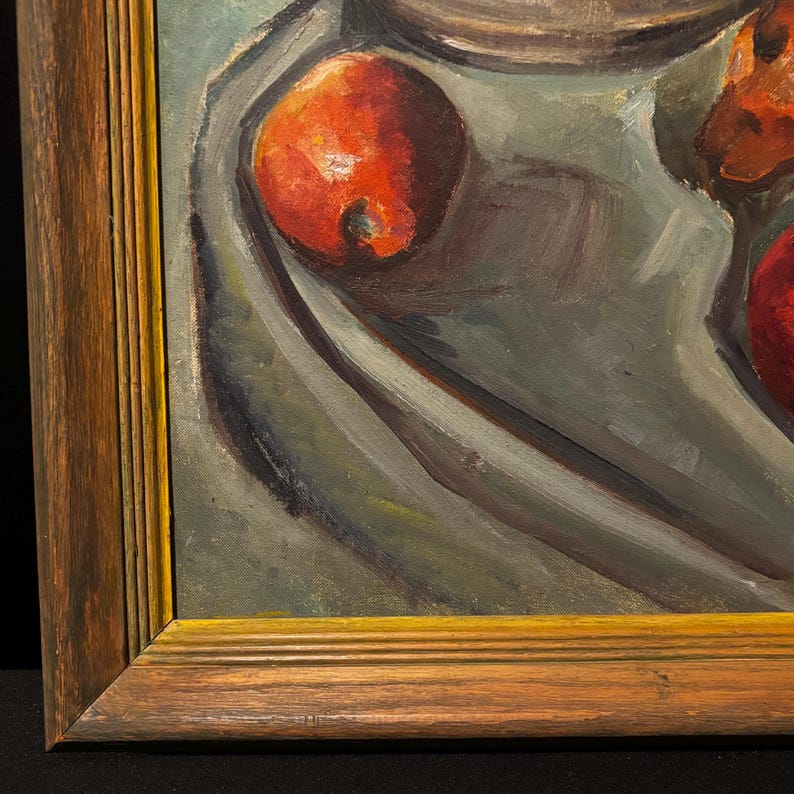 May include: Oil painting of a still life with red pomegranates and a draped cloth. The pomegranates are a vibrant red, contrasting with the muted gray and green background. The painting is framed in a wooden frame.