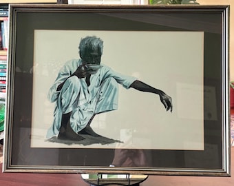 May include: Framed artwork depicting a person in light blue clothing, squatting and holding a small dish. The person has dark skin and white hair. The artwork is in a dark frame with a gold trim.