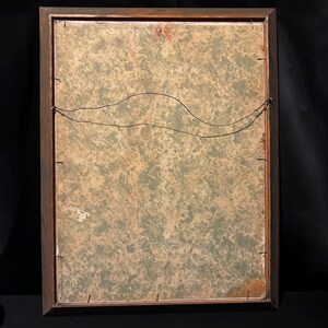 May include: Back of a framed artwork with a brown wooden frame. The artwork's backing has a mottled green and tan pattern. A black wire is strung across the back for hanging. The frame is rectangular.