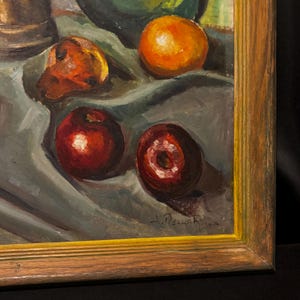 May include: Oil painting of a still life with fruit. The painting features a wooden frame and depicts a collection of oranges, apples, and other fruits on a draped surface. The colors are warm, with shades of red, orange, and brown.