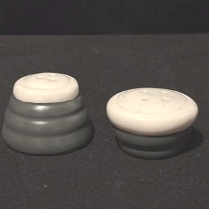 Puede incluir: Un juego de tres tazas de cerámica con un acabado mate moteado. Las tazas son de color crema, gris claro y gris oscuro. Cada taza tiene un diseño simple y minimalista y un asa redondeada.