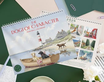 May include: A spiral-bound wall calendar titled "The Dogs of Character 2026 Wall Calendar." The cover features a coastal scene with a lighthouse and dogs in a boat. The open calendar shows dog illustrations and the year 2026.