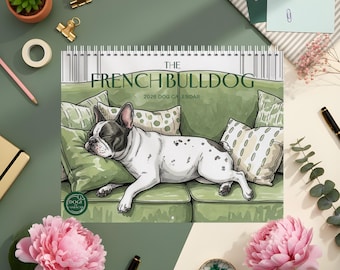 May include: A 2026 calendar featuring a French Bulldog illustration resting on a green sofa with pillows. The calendar's title reads "The French Bulldog". The image is surrounded by stationery and pink flowers.