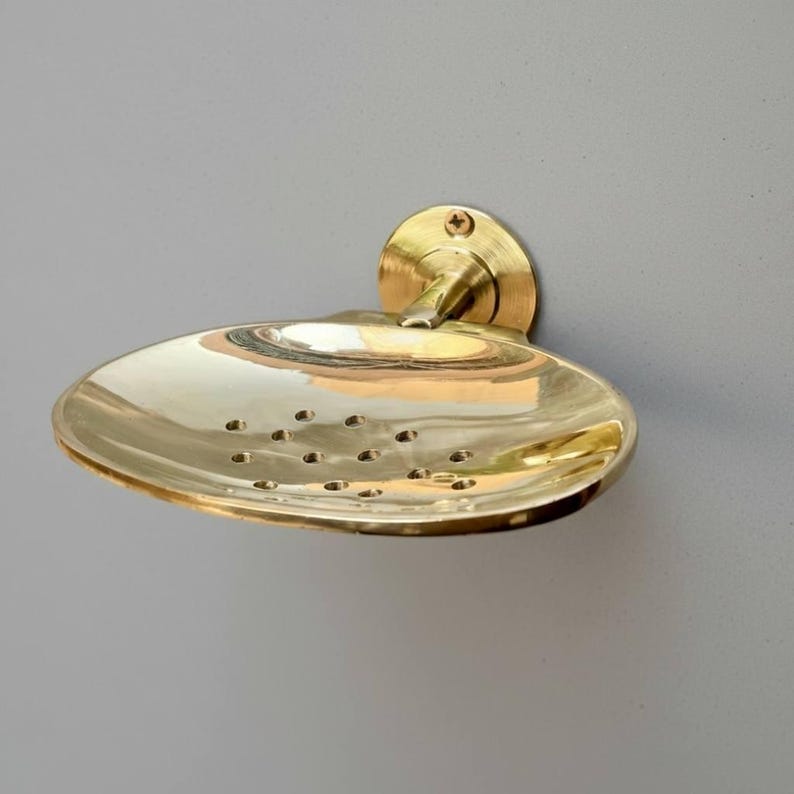 Detailed shot of unlacquered brass soap dish base and arm mount with warm polished tone.
