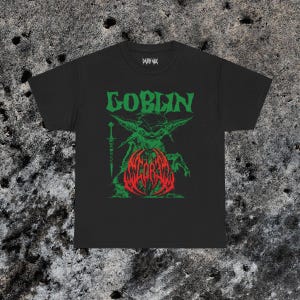 May include: Black t-shirt with a green and red graphic. The graphic features the word "GOBLIN" in green above a green goblin-like creature holding a sword. Below the creature is the word "SCORBA" in red.