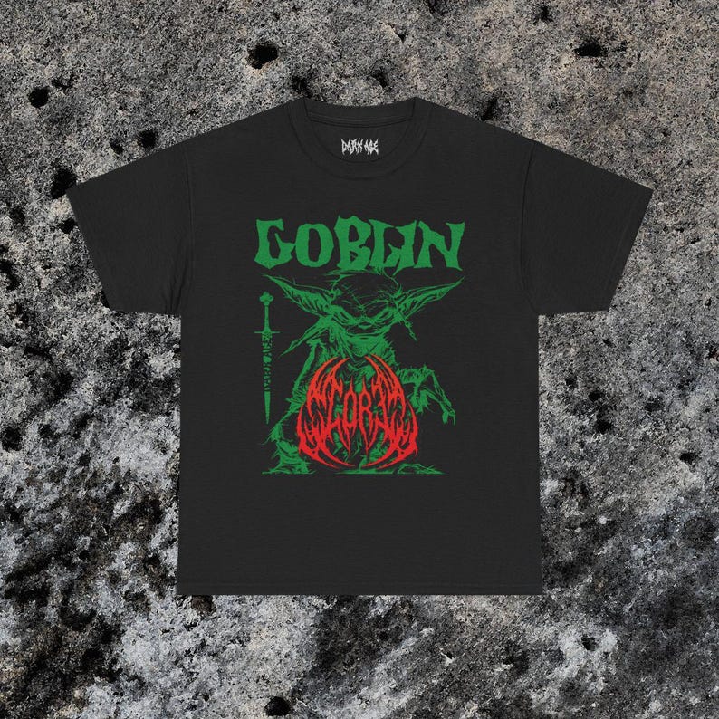 May include: Black t-shirt with a green and red graphic. The graphic features the word "GOBLIN" in green above a green goblin-like creature holding a sword. Below the creature is the word "SCORBA" in red.