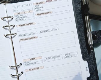 May include: A dark gray felt binder with a six-ring metal mechanism holding white paper inserts. The page is a Diagnostic Visit Log with fields for facility, test, vitals, and notes. A silver pen is clipped to the side of the binder cover.