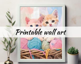 May include: A framed print featuring two kittens peeking over a basket of colorful yarn balls. The kittens have blue and brown eyes. The text "Printable wall art" is displayed across the image. The artwork is set against a soft, pastel background.