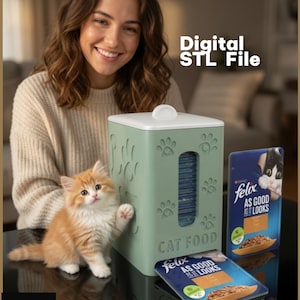 Puede incluir: Un dispensador rectangular de color verde salvia para sobres de comida para gatos con huellas en relieve y el texto CAT FOOD. El dispensador tiene una tapa blanca y una ranura vertical para sobres Felix As Good As It Looks.