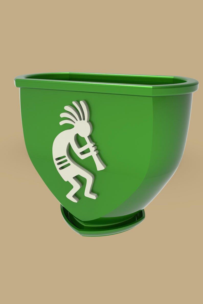 Puede incluir: Una jardinera verde con un dise&ntilde;o de Kokopelli blanco. La jardinera tiene una forma redondeada con una base plana y un borde alrededor de la parte superior. La figura de Kokopelli toca la flauta.