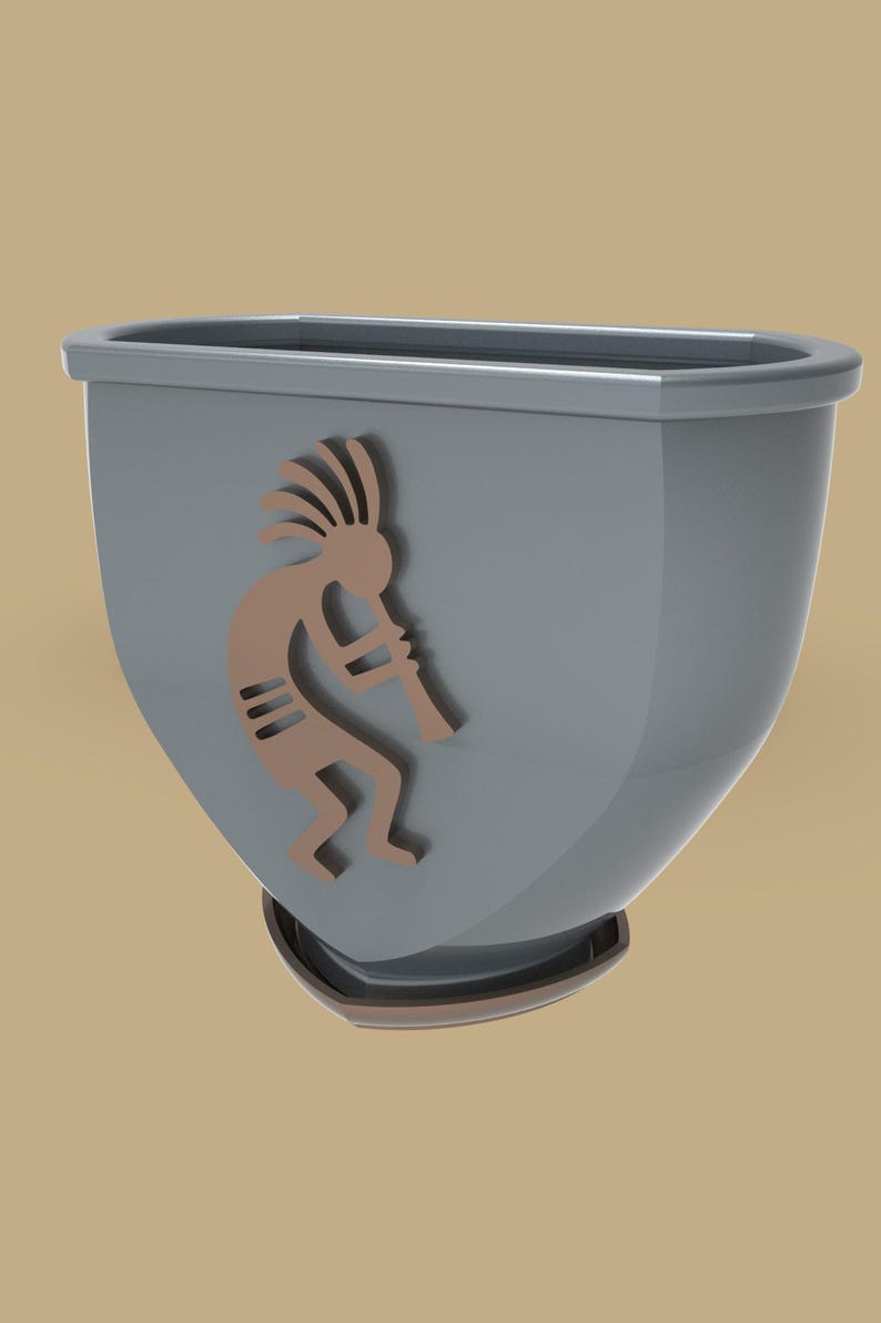 Puede incluir: Una maceta gris con un dise&ntilde;o de Kokopelli marr&oacute;n. La maceta tiene forma redondeada con la parte superior plana y una base peque&ntilde;a. La figura de Kokopelli toca la flauta. Para uso interior o exterior.