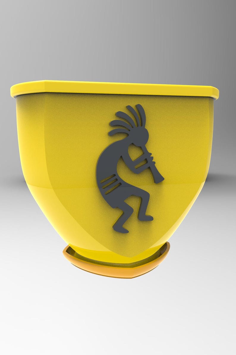Puede incluir: Un recipiente decorativo amarillo con una figura Kokopelli gris oscuro tocando una flauta. El recipiente tiene una base redondeada y una parte superior rectangular con un fino borde naranja-marr&oacute;n.