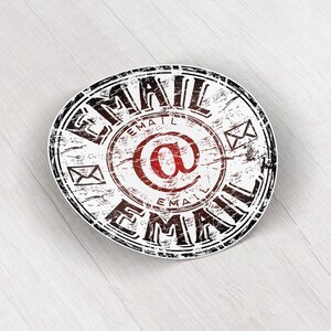 May include: A circular sticker with a distressed design. The word "EMAIL" is in a bold, black font around the edge. The centre features a red "@" symbol, surrounded by the word "EMAIL" and small envelope icons. The background is white.