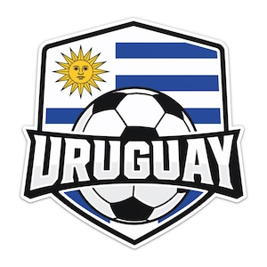 Puede incluir: Una pegatina en forma de escudo con la bandera de Uruguay y su emblema de sol amarillo, superpuesta con un gráfico de balón de fútbol en blanco y negro y una banda negra central que contiene las letras mayúsculas blancas URUGUAY.