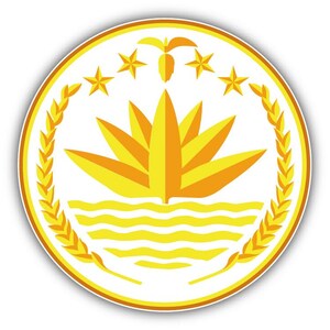 Op de afbeelding: Een cirkelvormig embleem met een witte achtergrond, met een centraal lotusbloemontwerp in tinten geel en oranje. Boven de bloem bevinden zich vijf gouden sterren en een gestileerde banaan. Het embleem is omcirkeld door een tarwekrans en een gouden rand.