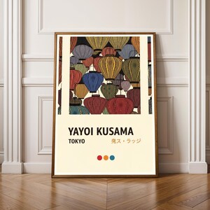 May include: A framed art print featuring a colorful pattern of lanterns in various colors, including red, blue, yellow, and green. The print includes the text "YAYOI KUSAMA TOKYO" and Japanese text. The artwork is displayed on a light-colored wall.