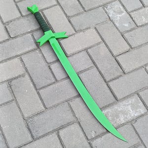 May include: A bright green sword with a cross-shaped guard and a leaf-like design on the pommel. The handle is wrapped in black material. The sword is lying on a gray brick surface.