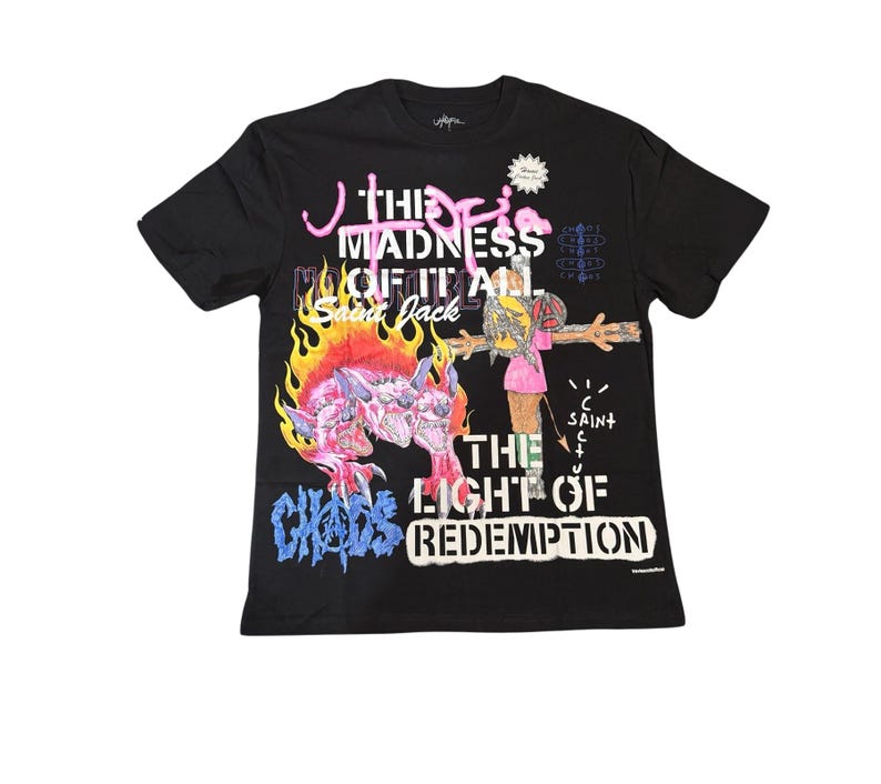 May include: Black t-shirt with a colorful graphic design. The design includes text that reads "THE MADNESS OF IT ALL" and "THE LIGHT OF REDEMPTION". A cartoon-like figure is depicted with flames and other illustrations.