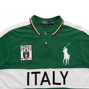 Pu&ograve; includere: Polo verde con dettagli bianchi e la scritta "ITALY" sul petto. Presenta una toppa con "ITA11" e un logo di giocatore di polo bianco. Il colletto ha finiture rosse e bianche.