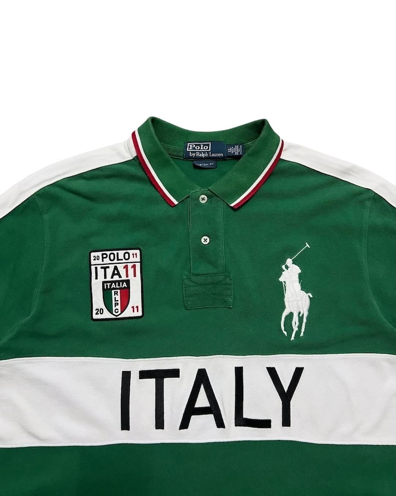 Pu&ograve; includere: Polo verde con dettagli bianchi e la scritta "ITALY" sul petto. Presenta una toppa con "ITA11" e un logo di giocatore di polo bianco. Il colletto ha finiture rosse e bianche.