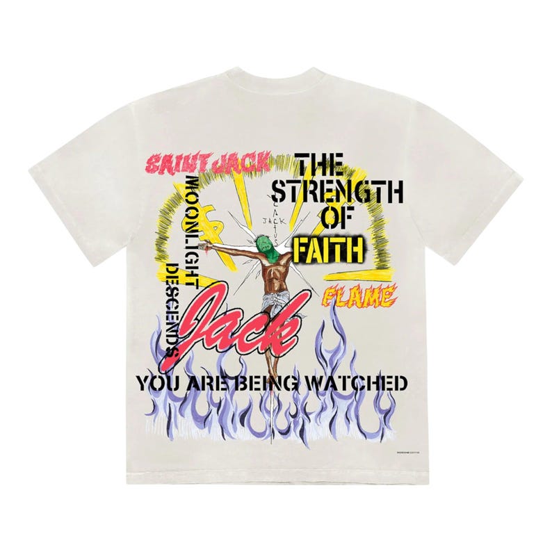 May include: Cream-colored t-shirt with a graphic design featuring the text "SAINT JACK" and "THE STRENGTH OF FAITH." The design includes an illustration of a figure with a green mask and the words "YOU ARE BEING WATCHED."