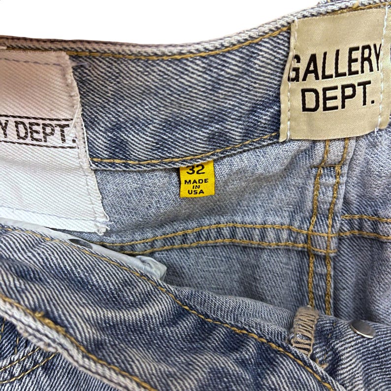 May include: Close-up of light-wash denim jeans with visible stitching. The jeans have a yellow tag that reads "32 MADE IN USA." The "GALLERY DEPT." label is also visible.