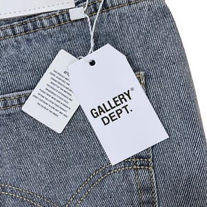 May include: Close-up of denim fabric with a white tag that reads "GALLERY DEPT." in black block letters. A smaller tag with text is also visible. The denim has visible stitching and a faded appearance.