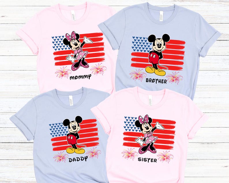 May include: Four short-sleeved t-shirts in pink and light blue, each featuring a cartoon character design. The designs include Mickey and Minnie Mouse in front of a stylized American flag, with the words "mommy", "brother", "daddy", and "sister" below.