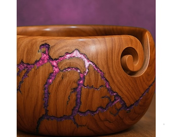 Könnte beinhalten: Eine handgefertigte Garnschale aus Holz mit einer satten braunen Oberfläche. Die Schale hat ein einzigartiges Design mit leuchtend rosa Harzakzenten, die Blitzen ähneln. Eine spiralförmige Garnführung ist in die Seite geschnitzt.