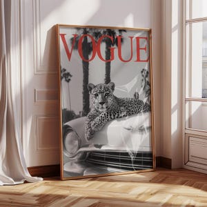 May include: Framed Vogue magazine cover art featuring a black and white image of a leopard resting on a classic car. The word "VOGUE" is in red at the top. Palm trees are in the background.