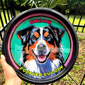 May include: A round black tray featuring a colorful portrait of a dog with the name "MICHO" above the dog's head. The words "FOREVER OUR BOY" are printed around the bottom edge of the tray. The dog has black, brown, white, and blue fur.