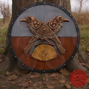 Könnte beinhalten: Ein runder Holzschild mit detailliertem Raben-Design. Der Schild hat ein zweifarbiges Farbschema mit grauem und braunem Hintergrund und ein bronzefarbenes Raben-Emblem. Der Schild hat einen Durchmesser von etwa 76 cm.