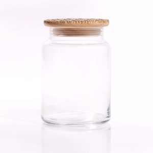 May include: A clear glass jar with a wooden lid. The jar is empty and has a smooth, rounded shape.
