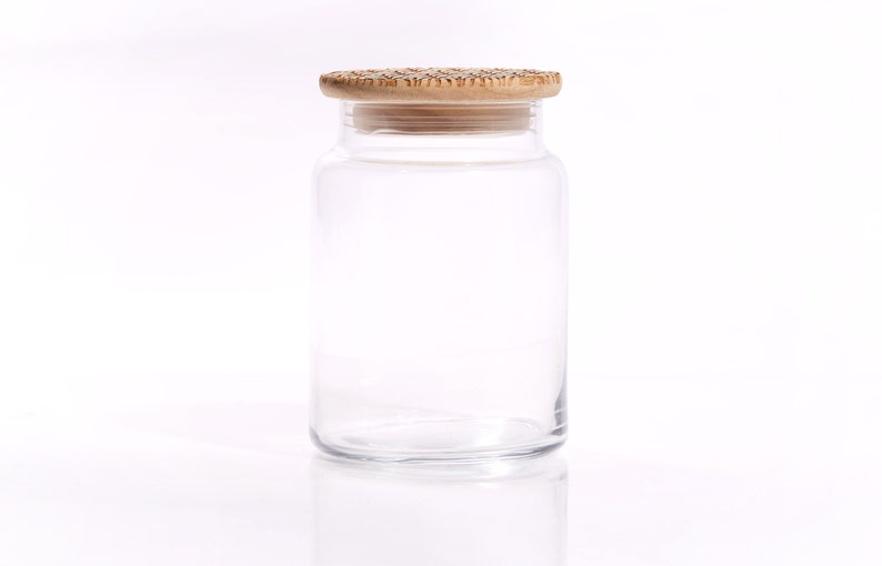 May include: A clear glass jar with a wooden lid. The jar is empty and has a smooth, rounded shape.