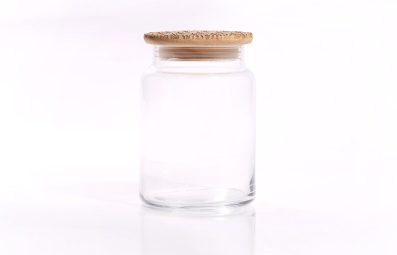 May include: A clear glass jar with a wooden lid. The jar is empty and has a smooth, rounded shape.