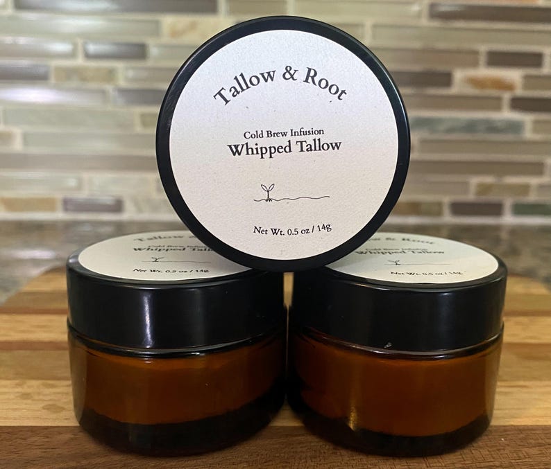 May include: Three small jars of whipped tallow with black lids and brown glass. The labels read "Tallow & Root" and "Whipped Tallow." Each jar contains 0.5 oz / 14g of product. The jars are arranged on a wooden surface.