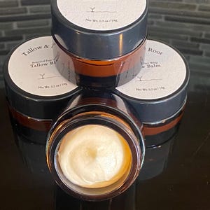 May include: A stack of four small, brown glass jars of Tallow Balm. Each jar has a white label with black text that reads "Tallow & Root" and "Botanical Face Whip Tallow Balm". The jars contain a creamy, off-white balm. Each jar is 0.3 oz / 14g.