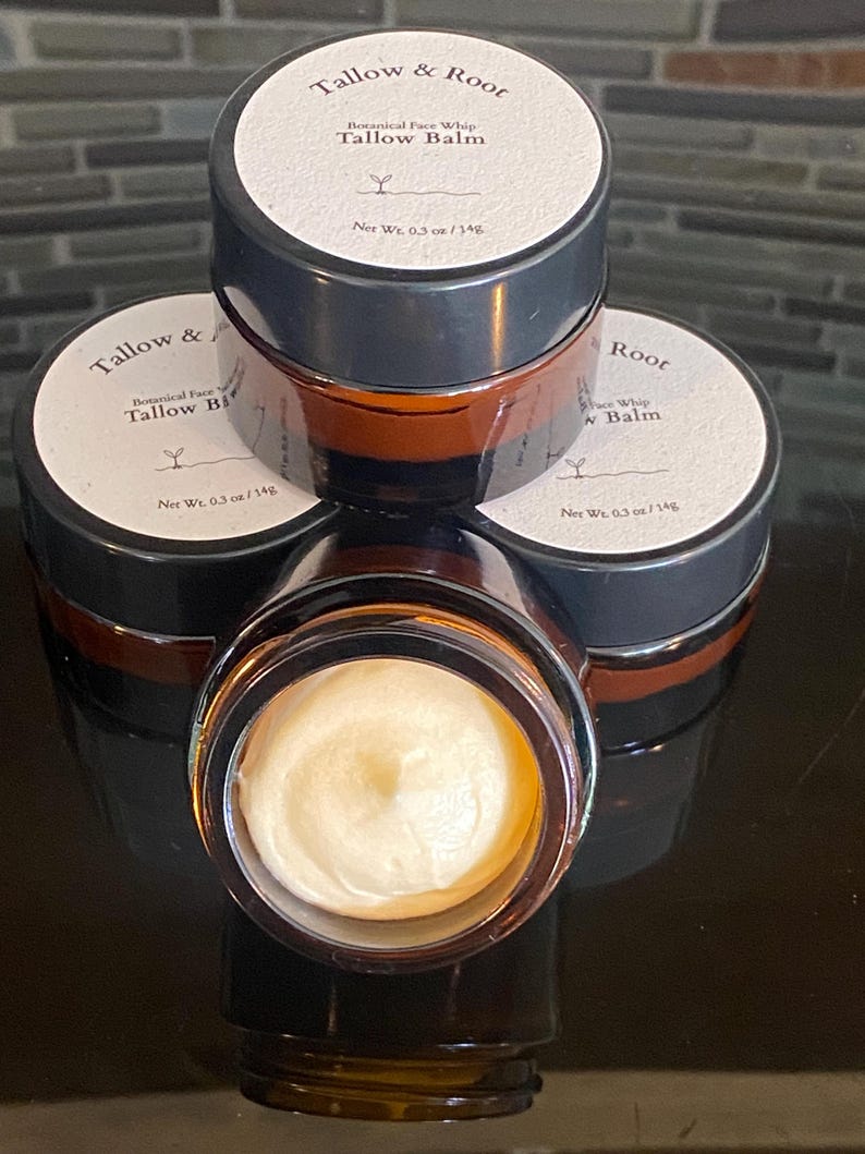 May include: A stack of four small, brown glass jars of Tallow Balm. Each jar has a white label with black text that reads "Tallow & Root" and "Botanical Face Whip Tallow Balm". The jars contain a creamy, off-white balm. Each jar is 0.3 oz / 14g.