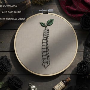 以下が含まれることがあります： ベージュ色の生地の刺繍枠には、上部に緑の葉が付いた背骨のデザインが施されています。「PDF INSTANT DOWNLOAD」、「FULL STITCH AND DMC GUIDE」、「BASIC STITCHES TUTORIAL VIDEO」の文字が見えます。黒いバラやその他のゴシック様式の要素がフレームを囲んでいます。