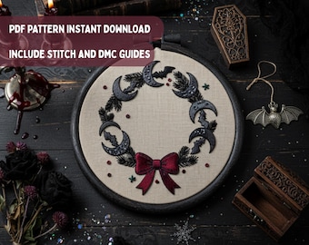 Può includere: Un telaio da ricamo con un motivo a ghirlanda circolare su tessuto beige, caratterizzato da lune crescenti nere, rami di pino e piccoli pipistrelli, completato da un fiocco rosso scuro. Testo: PDF PATTERN INSTANT DOWNLOAD INCLUDE STITCH AND DMC GUIDES.