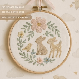 May include: Embroidered hoop art with a bunny, fawn, and bird surrounded by flowers and foliage. The design includes a large pink flower at the top, set against cream fabric. The text "PDF INSTANT DOWNLOAD", "COLOR AND STICH GUIDE", and "BASIC STITCHES TUTORIAL VIDEO" is visible.