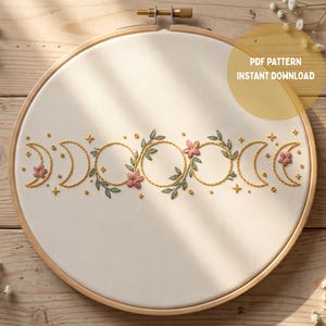 Peut inclure: Un tambour à broder contenant un tissu blanc avec un motif de phases lunaires brodé en fil jaune, agrémenté de feuilles vertes et de petites fleurs roses. Le texte PDF PATTERN INSTANT DOWNLOAD est imprimé dans le coin supérieur droit.