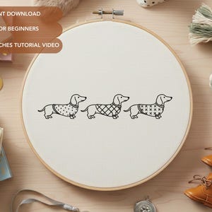 Puede incluir: Bastidor de bordado con tres perros salchicha con suéteres. El texto en la imagen dice "PDF INSTANT DOWNLOAD", "PERFECT FOR BEGINNERS" y "BASIC STITCHES TUTORIAL VIDEO". El bastidor está sobre una superficie de madera con otros suministros.