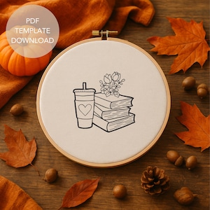 May include: A black and white embroidery hoop with a coffee cup, books, and floral design. The text "PDF TEMPLATE DOWNLOAD" is in a white circle in the upper left corner. The background includes fall leaves, acorns, and a small pumpkin.