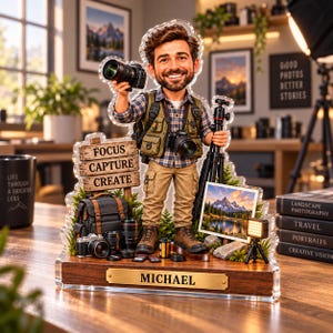May include: A custom acrylic figurine of a photographer wearing a plaid shirt and vest, holding a camera and tripod. The base features a wooden plaque with the name MICHAEL and a sign reading FOCUS CAPTURE CREATE, surrounded by camera gear.