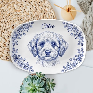 Könnte beinhalten: Ovale weiße Servierplatte mit blauem Blumenrand und detaillierter Skizze eines Hundegesichts. Der Name "Chloe" steht über dem Hund. Das Design erinnert an klassisches blau-weißes Porzellan.