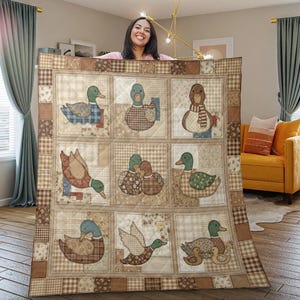 May include: A square patchwork quilt featuring nine distinct panels, each displaying a different duck illustration in shades of brown, beige, and cream. The quilt has a checkered border and a quilted texture throughout the fabric surface.