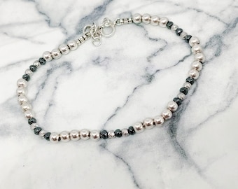 Puede incluir: Pulsera de cuentas plateadas con cuentas plateadas y gris oscuro alternas. La pulsera tiene un diseño delicado y un cierre seguro. Un accesorio elegante para el uso diario.